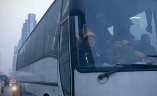 Des salariés chinois prennent un bus devant un chantier à Pékin le 28 décembre 2015