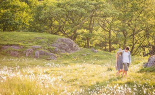 Couple walking in field, Cumbria, England, UK