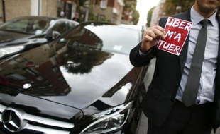 Un chauffeur Uber manifeste à Paris, montrant un autocollant déplorant "Uber m'a tuer", le 13 octobre 2015 à Paris