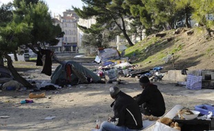 Des personnes sont assises sur un matelas, le 2 décembre 2010, dans le quartier de la porte d'Aix à Marseille, où plusieurs familles roms se sont installées depuis quelques semaines faute de logement.