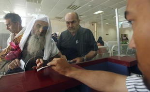 Un agent de frontière vérifie les passeports des Palestiniens qui viennent franchir légalement la frontière entre Gaza et l'Egypte, à Rafah, le 28 mai 2011
