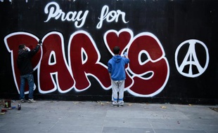 Deux jeunes hommes peignent un graffiti en hommage aux victimes des attentats, le 14 novembre 2015 à Paris