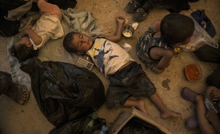 Un enfant dort alors que des dizaines de femmes et d'enfants apparentés à des combattants de Daesh attendent pour monter à bord d'autobus et de camions, laissant le camp surpeuplé d'al-Hol, lundi 3 juin 2019.