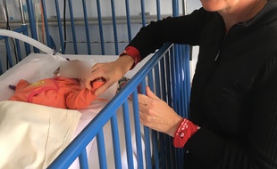 L'un des bébés de Chloé, qui a lancé un appel pour que l'on vienne câliner ses jumeaux, avec une bénévole.