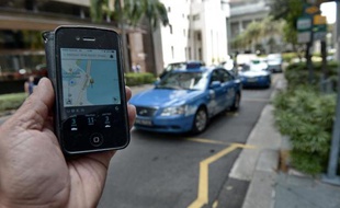 Une personne utilise avec son smartphone l'application Uber, le service américain de voitures avec chauffeur (VTC), le 10 octobre 2014 à Singapour