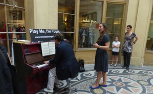 Des passants s’essayant au piano mis à disposition galerie Vivienne à Paris (2e), le 25 juin 2014