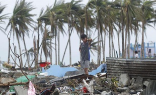 Un jeune homme sur les ruines de sa maison après le passage du typhon Haiyan, à Tacloban, aux Philippines, le 12 novembre 2013.