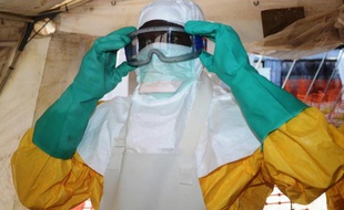 Un membre de Médecins Sans Frontières s'équipe de vêtements de protection pour entrer dans une zone d'isolement pour malades ayant contracté le virus Ebola, le 28 juin 2014 à Conakry