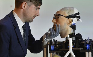 Swiss social psychologist Bertolt Mayer views 'Rex', a two metre tall artificial human, at the Science Museum in central London February 5, 2013. Mayer, a who uses a prosthetic hand himself, was used as the model for the 'bionic man', whom the British roboticist designers claim is the world's first complete bionic man, featuring artificial organs as well as fully functioning limbs. It will be on public display until March 11.