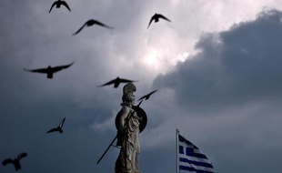 Le drapeau grec flotte devant une statue d'Athéna, dans le centre d'Athènes, le 12 mars 2015