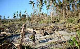 Une femme porte des bananes sur une plage du Vanuatu le 21 mars 2015 après le passage du cyclone Pam.