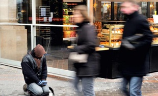 Des personnes passent devant un mendiant le 13 décembre 2012 à Lille