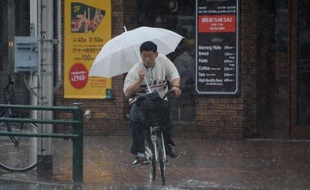 Un cycliste sous une pluie battante dans le quartier commerçant de Ginza à Tokyo le 29 juin 2014