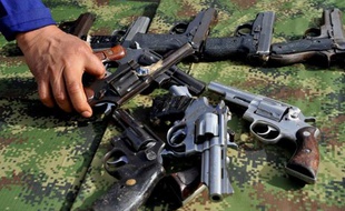 Un soldat colombien saisit une des 9.517 armes saisies aux mains des guérilleros des Farc et de l'ELN avant que celles-ci ne soient fondues pour être recyclées, le 25 novembre 2014 à Sogamoso, en Colombie