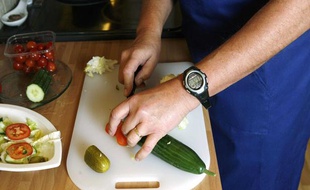 Un homme découpe des légumes.