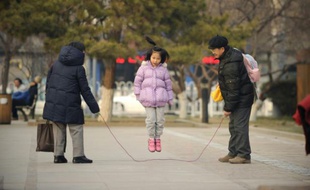 Une petite fille joue à la corde à sauter avec sa famille à Pékin, le 7 décembre 2012
