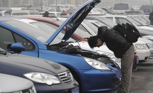 Un homme inspecte une voiture d'occasion (illustration).