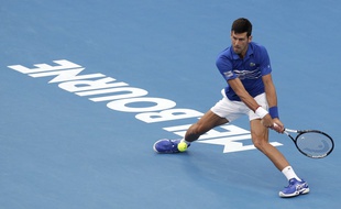 Serbia's Novak Djokovic makes a backhand return to France's Lucas Pouille during their semifinal at the Australian Open tennis championships in Melbourne, Australia, Friday, Jan. 25, 2019.