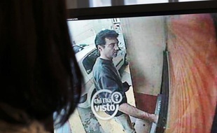 A picture taken on May 11, 2011, in Paris shows a woman looking at a still frame taken from a surveillance camera, and released on the Italian RAI TV website, of Xavier Dupont de Ligonnes, a man suspected of murdering his family, withdrawing cash from an ATM in Roquebrune-sur-Argens on April 14. French authorities issued an international arrest warrant on May 10, 2011 for Xavier Dupont de Ligonnes, suspected of murdering his wife and four children before going on the run. AFP PHOTO THOMAS COEX