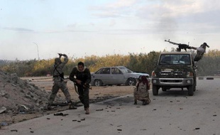 TOPSHOTS Des membres des forces armées libyennes tirent en direction de milices islamistes, le 3 novembre 2014, près du port de Benghazi, dans l'est du pays.