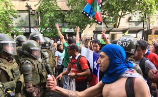 Des manifestants font face aux forces de l'ordre aux abords du palais présidentiel à Santiago du Chili le 26 octobre 2019.