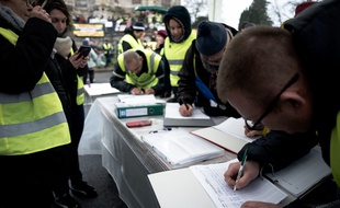 Des "gilets jaunes" écrivent leurs doléances en marge d'une manifestation.
