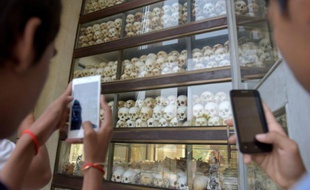 Des visiteurs prennent en photo des crânes des victimes des Khmers rouges au mémorial de Choeung Ek à Phnom Penh, le 17 avril 2016