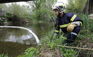 Un pompier surveille un barrage flottant installé sur la rivière le Largue à Saint-Maime, le 02 mai 2010 après une fuite d'hydrocarbure dans une entreprise.