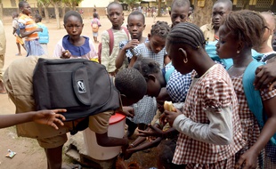 Ivorian schoolchildren wait in line to wash their hands prior to go to school on October 23, 2014 in a primary school in Bouake. The Ivory Coast, currently free of the Ebola epidemic ravaging its neighbours, has launched a hunt for a Guinean health worker who may have fled his home country after possibly catching the disease. AFP PHOTO / ISSOUF SANOGO