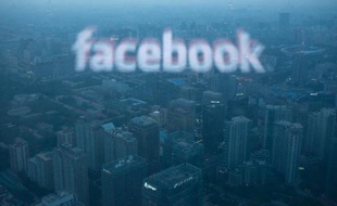 Une photo d'un écran d'ordinateur diffusant le logo de Facebook se reflétant sur la vue aérienne de Pékin le 16 mai 2012