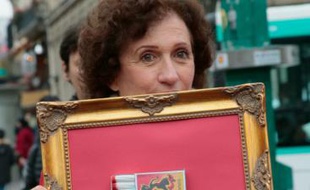 Une femme porte un cadre avec une boite d'allumettes contenant des tampons hygiéniques, le 11 novembre 2015 à Paris