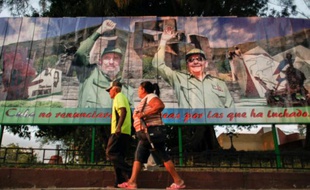 Un couple passe devant une affiche de l'ancien président de Cuba Fidel Castro et de l'actuel Raul Castro, à Guantanamo le 13 mars 2016