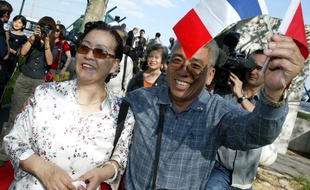 Les premiers touristes chinois «officiels» en provenance de Pékin brandissent des drapeaux francais et chinois, le 01 septembre 2004 à leur arrivée à l'aéroport de Roissy.