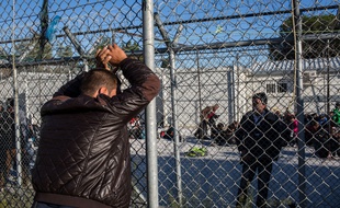 Camp de Moria sur l'île grecque de Lesbos. Un migrant discute avec un autre, qui se trouve a l'intérieur du hotspot, le 27 octobre 2015.