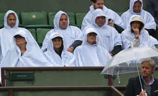 Des spectateurs se protègent de la pluie sur le Central de Roland-Garros le 31 mai 2016.
