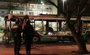 Des policiers se tiennent devant le bus de voyageurs partiellement incendié dans la cité du Grand Ensemble, à Tremblay-en-France, le 31 mars 2010.