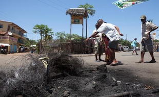 Des passants devant le lieu où a lieu le lynchage de trois personnes à Madagascar le samedi 5 octobre 2013.