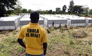 Un homme portant un T-shirt "Ebola est réel" regarde le nouveau centre de traitement des malades atteints du virus Ebola à Monrovia, le 28 septembre 2014