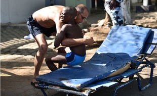 Un homme aide un enfant blessé lors d'une attaque par des gens d'armés de la station balnéaire de Grand-Bassam, en Côte d'Ivoire.