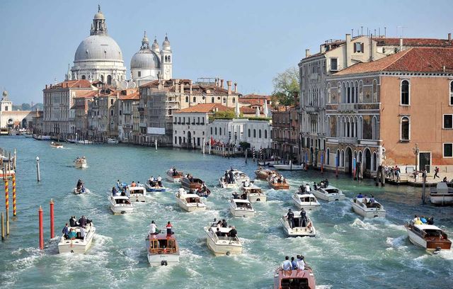 Vous avez vu la photo « officielle », avec Georges et Amal seuls au monde sur une vedette en route vers la lagune de Venise. Et voici la « vraie » vie : autour de l’embarcation : il y avait un peloton entier composé de journalistes et de membres de la sécurité. Moins romantique.