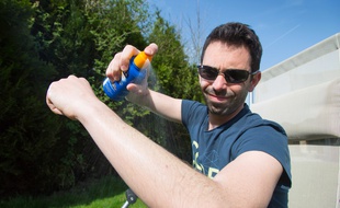 Un homme applique de la crème solaire sur son bras.