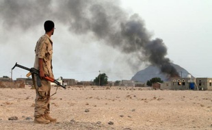 Un combattant yéménite des Comités de résistance populaire regarde de la fumée s'élever d'un bâtiment à l'ouest d'Aden, dans le sud du pays, le 12 juillet 2015