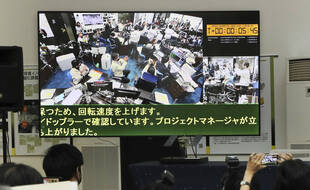 Le travail des scientifiques de l'agence spatiale japonaise retransmis à la télévision, le 5 décembre 2020.