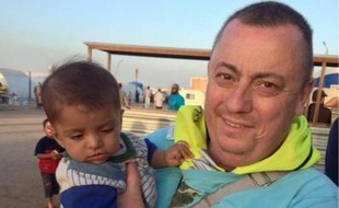 Alan Hennning, portant un enfant dans un camp de réfugiés à la frontière entre la Syrie et la Turquie, dans une photo fournie le 15 septembre 2014 par le Foreign Office