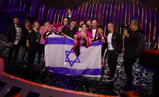 Netta porte le trophée de l'Eurovision 2018, entourée de ses danseuses et de sa délégation, sur la scène du concours à Lisbonne, le 13 mai 2018.