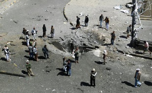 Des habitants autour d'un cratère provoqué par une frappe aérienne de la coalition arabe, le 1er octobre 2015 à Sanaa, au Yémen