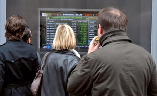 Des personnes regardent les cours de la Bourse dans une rue de Paris