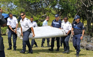 Des policiers transportent le débris d'avion suspect récupéré sur le littoral de l'île française de la Réunion, le 31 juillet 2015.