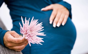 Femme enceinte tenant à la main une fleur