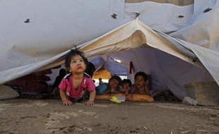 A Aski Kalak, à 40 kilomètres d'Erbil dans la zone autonome du Kurdistan irakien, des enfants dont les familles ont été déplacées tentent de se distraire sous une tente du HCR, le 17 juin 2014